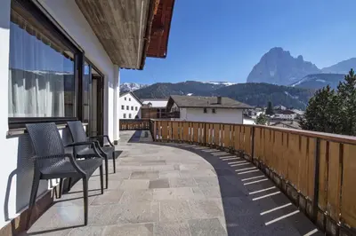 a balcony with chairs and a view of mountains at Apartments Praruf in Selva di Val Gardena