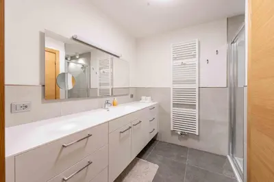 a white bathroom with a sink and a mirror at Casa al Parco Deluxe in Canazei