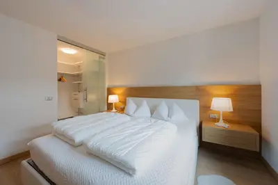 a bedroom with a large white bed and two lamps at Casa al Parco Deluxe in Canazei