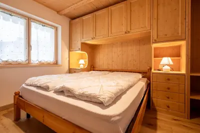 a bedroom with a large bed with wooden cabinets at Bilocale Fiore in Campitello di Fassa