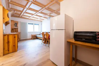 a kitchen with a refrigerator and a table with a microwave at Bilocale Fiore in Campitello di Fassa