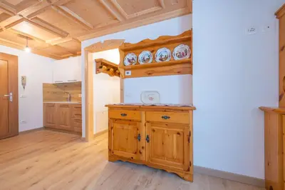 a kitchen with wooden cabinets and a wooden floor at Bilocale Fiore in Campitello di Fassa