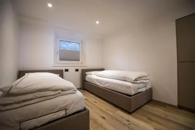 two beds in a bedroom with a window at Dolomites Apartments Cesa Benedet in Santa Cristina in Val Gardena