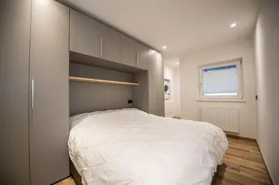 a bedroom with a large white bed and a window at Dolomites Apartments Cesa Benedet in Santa Cristina in Val Gardena