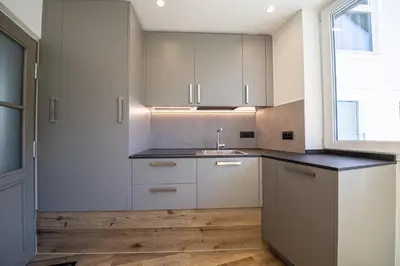 a kitchen with white cabinets and a sink and a window at Dolomites Apartments Cesa Benedet in Santa Cristina in Val Gardena