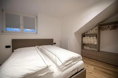 a bedroom with a bed with white sheets at Dolomites Apartments Cesa Benedet in Santa Cristina in Val Gardena