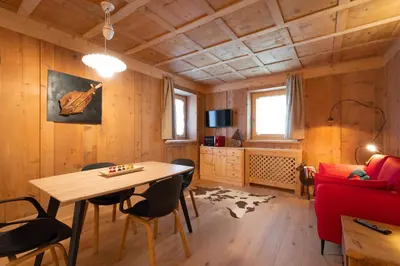 a living room with a table and chairs and a couch at Ciasa de Chica in Pozza di Fassa