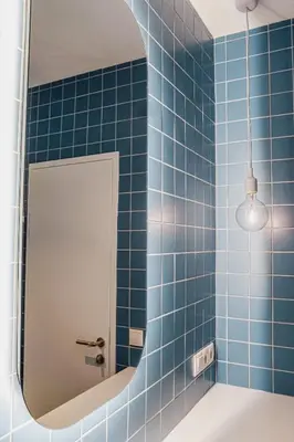 a bathroom with blue tiled walls and a mirror at Villa Kranebitt in Bressanone