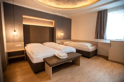 a hotel room with two beds and a table at Hotel Chrys in Bolzano