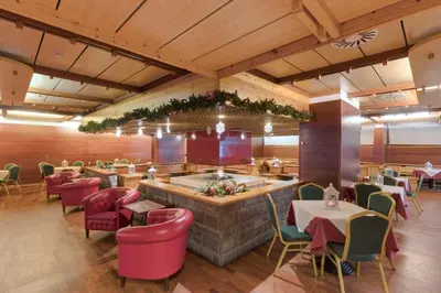 a restaurant with a bar with tables and chairs at Hotel Club Regina E Fassa in Mazzin