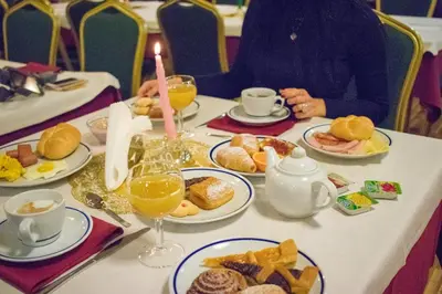 a table with plates of breakfast foods and a candle at Hotel Club Regina E Fassa in Mazzin