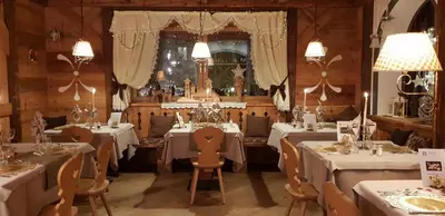 a dining room with white tables and chairs at Hotel Azola in Canazei