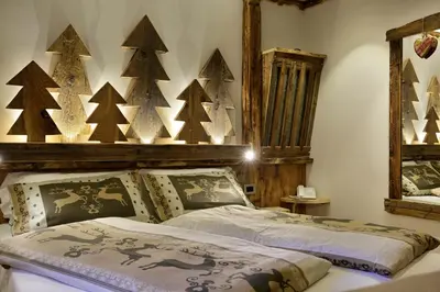 a bedroom with a bed with christmas trees on the wall at Hotel Azola in Canazei