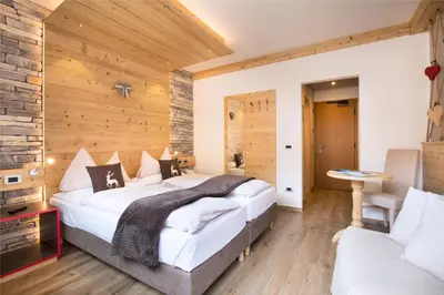 a bedroom with a large bed and a wooden wall at Hotel Azola in Canazei