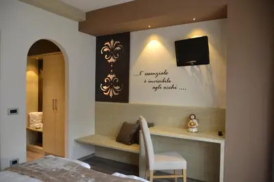 a bedroom with a bed and a tv on a wall at Hotel Azola in Canazei
