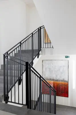 a staircase with black railings and a painting on the wall at Residence - Palais Hörtenberg in Bolzano