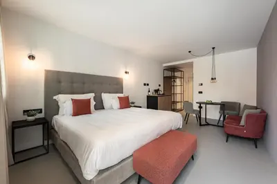 a bedroom with a large white bed and a red chair at Residence - Palais Hörtenberg in Bolzano