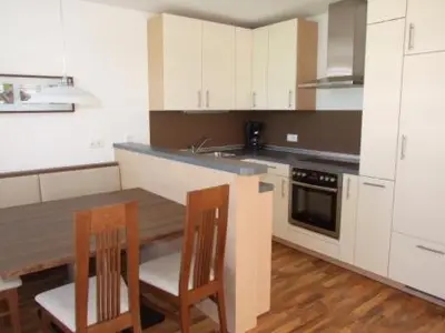 a kitchen with white cabinets and a table and two chairs at Tauberhof Apartments in Bressanone