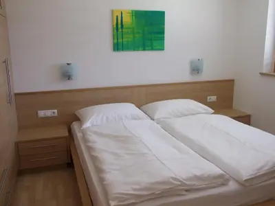 a bedroom with a bed with white sheets at Tauberhof Apartments in Bressanone