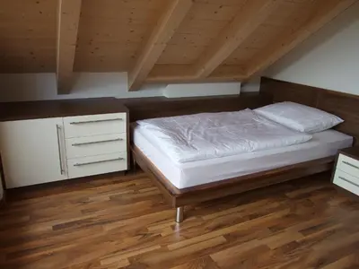 a bedroom with a bed and a wooden floor at Tauberhof Apartments in Bressanone