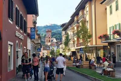 a group of people walking down a street with buildings at CASA BEBA - 2 camere, 2 bagni, parcheggio Dolomiti Affitti in Cavalese
