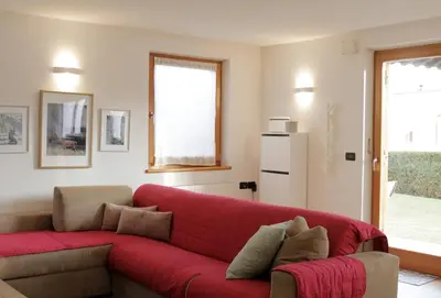 a red couch in a living room with a window at CASA BEBA - 2 camere, 2 bagni, parcheggio Dolomiti Affitti in Cavalese
