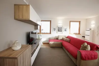 a living room with a red couch and a tv at CASA BEBA - 2 camere, 2 bagni, parcheggio Dolomiti Affitti in Cavalese