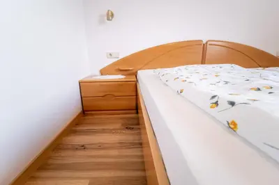 a bedroom with a bed and a wooden floor at Unterbrunnerhof in Lana