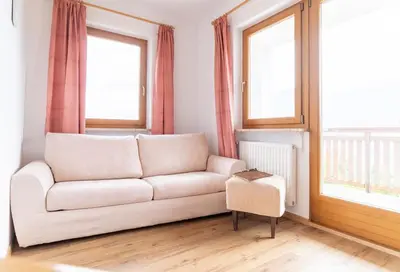 a white couch in a living room with windows at Unterbrunnerhof in Lana