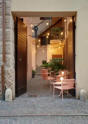 a patio with chairs and tables in a building at Goldengel Design-Suiten Frieda Maria im Herzen von Kaltern in Caldaro