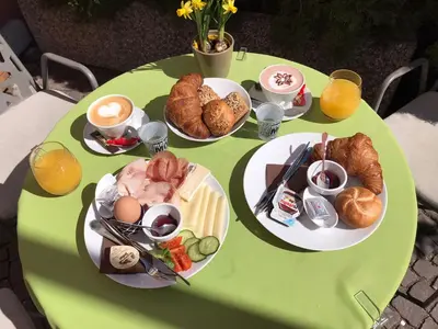 a green table topped with plates of food and pastries at Goldengel Design-Suiten Frieda Maria im Herzen von Kaltern in Caldaro