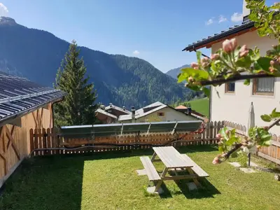 a picnic table in the grass next to a building at App Col di Lana - Agriturismo La Majon da Col in Colle Santa Lucia