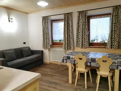 a living room with a table and chairs and a couch at App. Monte Pore - Agriturismo La Majon in Colle Santa Lucia