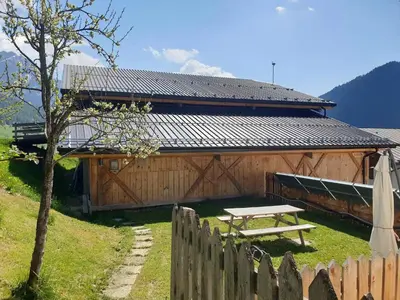 a wooden barn with a picnic table in front of it at App. Monte Pore - Agriturismo La Majon in Colle Santa Lucia
