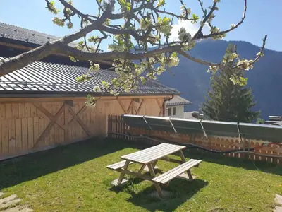 a wooden bench sitting in the grass next to a fence at App. Monte Pore - Agriturismo La Majon in Colle Santa Lucia