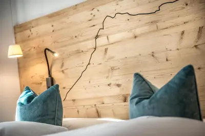 a bedroom with blue pillows on a bed with a wall at Chalet Prades Dolomiti Lodges in La Villa