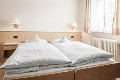 a bed with white sheets on it in a bedroom at Ciüf de Munt in Badia
