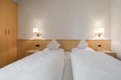 two beds in a room with white sheets and lights at Ciüf de Munt in Badia