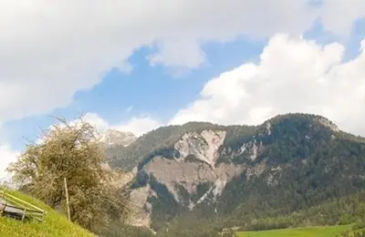 a mountain in the distance with a house on a hill at Galreidhof in Funes