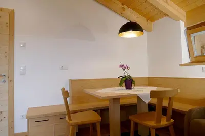 a dining room table with a vase of flowers on it at Der Luemerhof in Marlengo