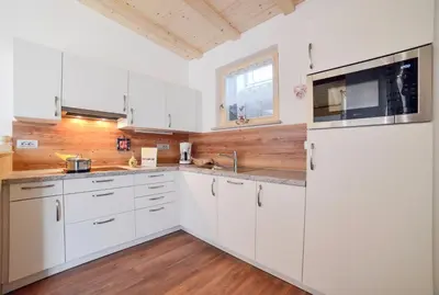 a kitchen with white cabinets and a white refrigerator at Residence Ravisa Dolomites in Selva di Val Gardena
