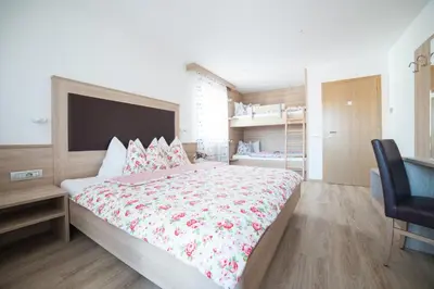 a bedroom with a large bed and a chair at Residence Ravisa Dolomites in Selva di Val Gardena