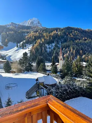 a view of a town in the snow with a church at Residence Ravisa Dolomites in Selva di Val Gardena