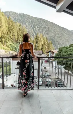 a woman in a dress walking on a balcony at Tyrol Living & Cafe in Nova Levante