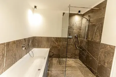 a bathroom with a tub and a glass shower at Tyrol Living & Cafe in Nova Levante