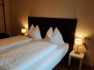 a bedroom with a bed with white pillows and two lamps at Tyrol Living & Cafe in Nova Levante