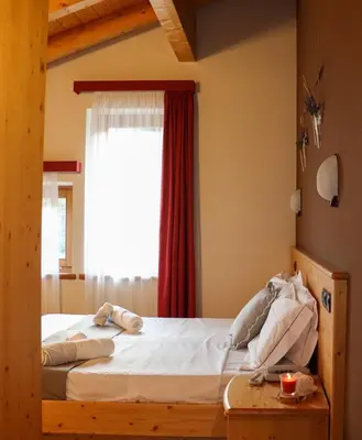 a bedroom with a large bed with a window at hotel Parco Pineta in Cavareno