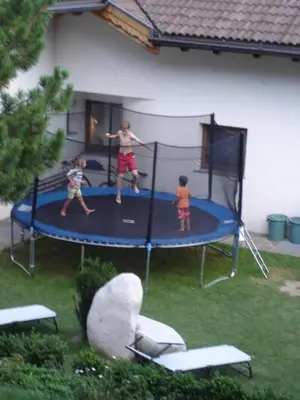 a woman and two children playing on a trampoline at Residence Klementhof 3 in Fiumes