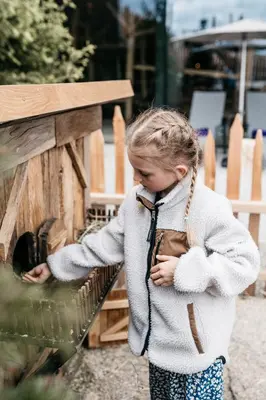 a little girl standing next to a wooden structure at Hotel Familiamus in Maranza