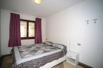 a bedroom with a bed and a window with purple curtains at Residence Roacia in Alba di Canazei